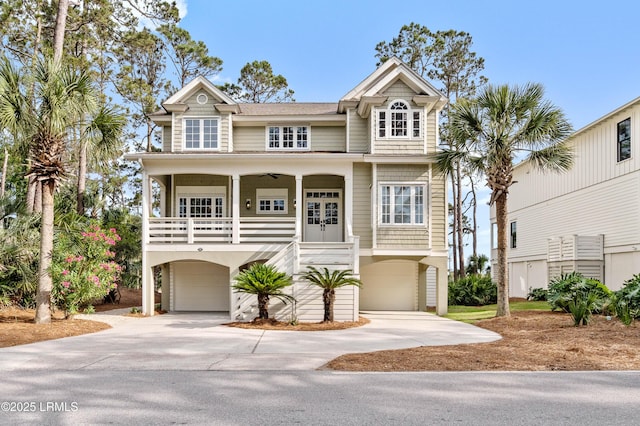 raised beach house featuring a garage, concrete driveway, and a porch