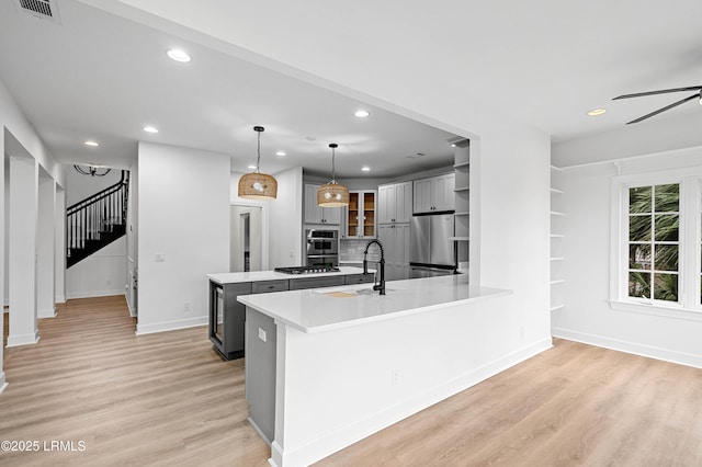 kitchen featuring stainless steel appliances, recessed lighting, a sink, light wood-style flooring, and a peninsula