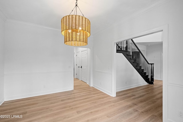 spare room with crown molding, stairs, a chandelier, wood finished floors, and baseboards