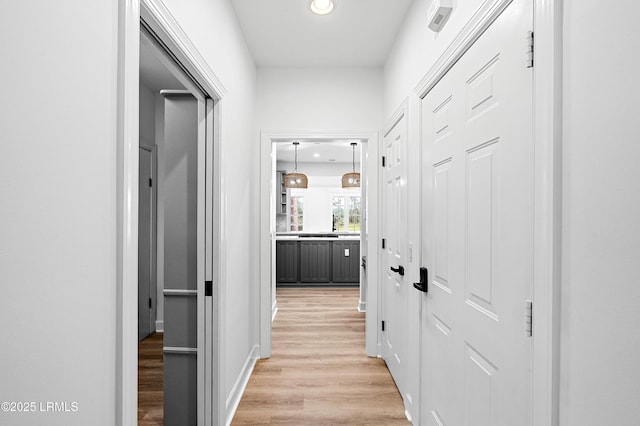 corridor with light wood finished floors, recessed lighting, and baseboards