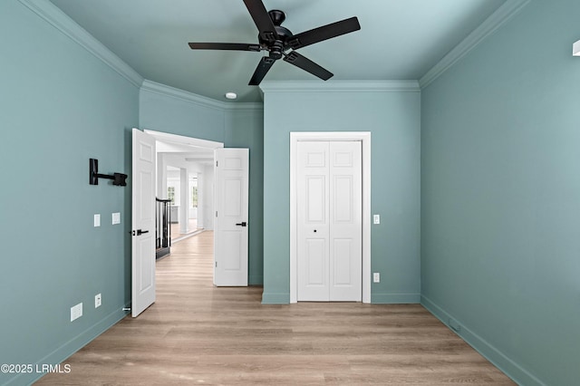 unfurnished bedroom featuring ornamental molding, baseboards, light wood-style floors, a closet, and ceiling fan