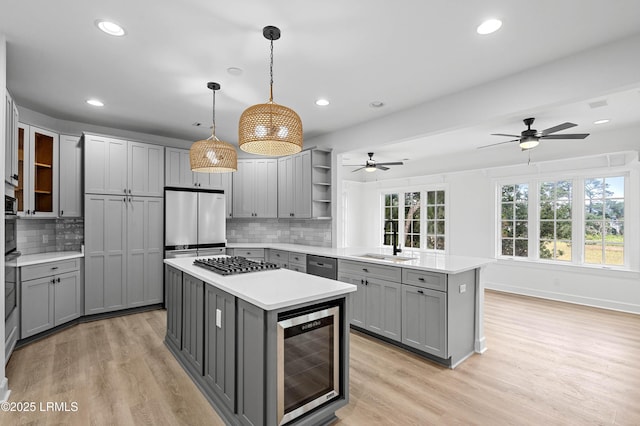 kitchen featuring gray cabinets, a sink, beverage cooler, a peninsula, and recessed lighting