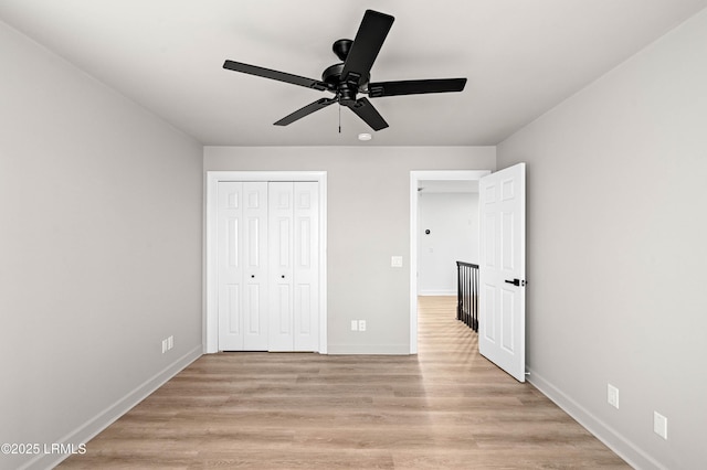 unfurnished bedroom featuring light wood-style flooring, a closet, baseboards, and a ceiling fan