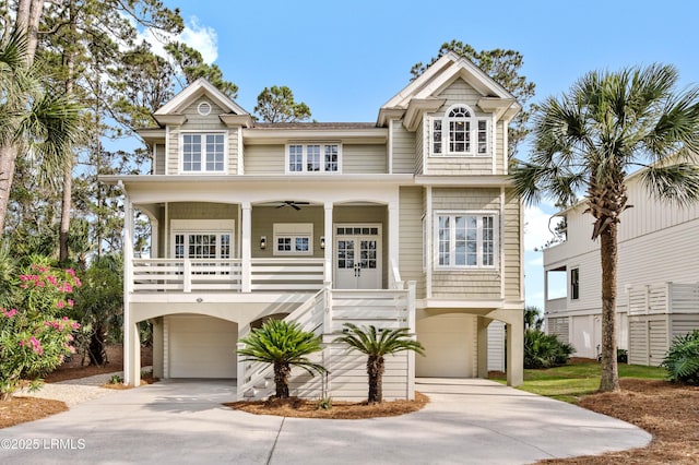 raised beach house with an attached garage, driveway, covered porch, and french doors