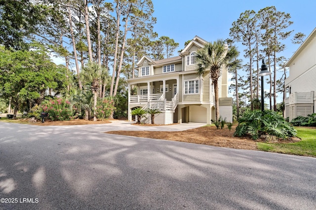 beach home featuring stairway, covered porch, and concrete driveway