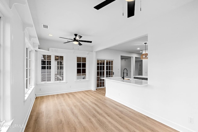unfurnished living room featuring a ceiling fan, baseboards, a sink, and recessed lighting
