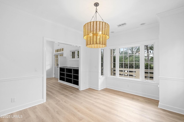 unfurnished dining area with ornamental molding, light wood-style floors, a chandelier, and baseboards