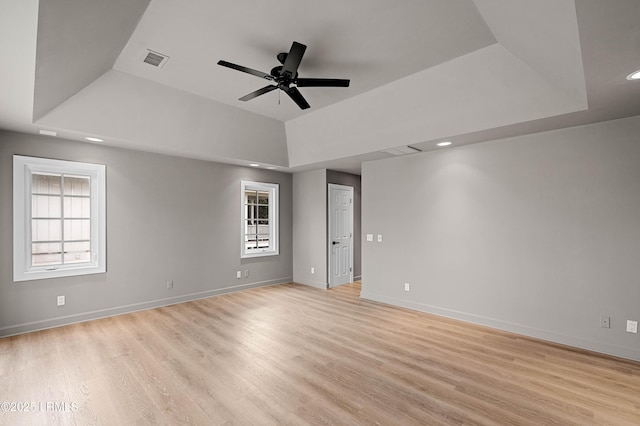 spare room featuring a raised ceiling, ceiling fan, light wood-style floors, and recessed lighting