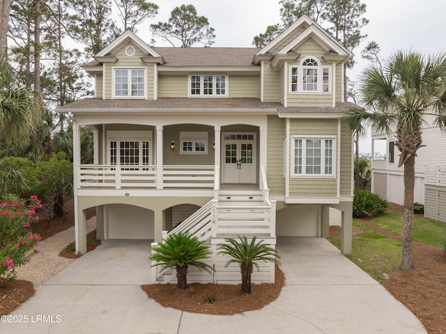 coastal inspired home with a garage, driveway, and stairs