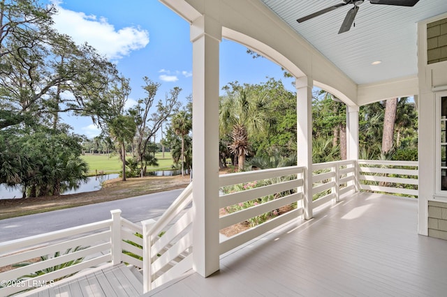 wooden porch featuring a water view and a ceiling fan