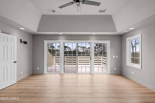 empty room featuring ceiling fan, recessed lighting, light wood-style flooring, baseboards, and a tray ceiling