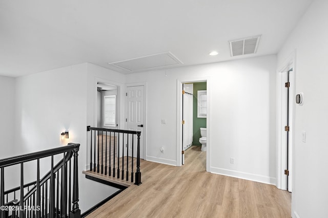 hall featuring an upstairs landing, attic access, wood finished floors, baseboards, and recessed lighting