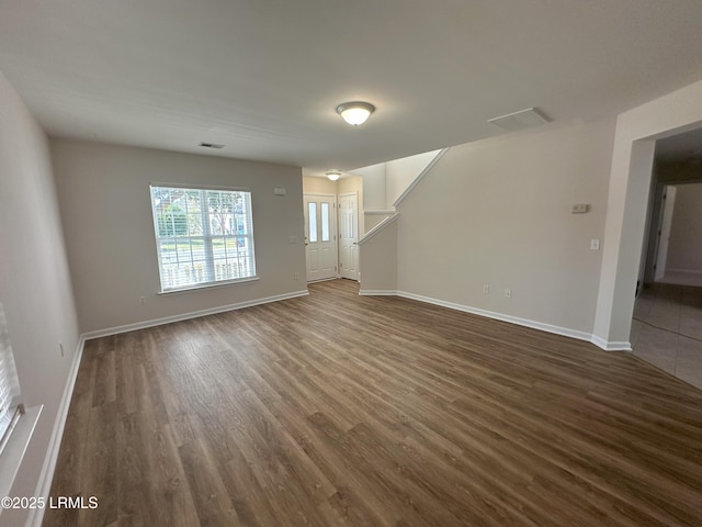 unfurnished living room featuring dark wood-style floors, baseboards, and visible vents