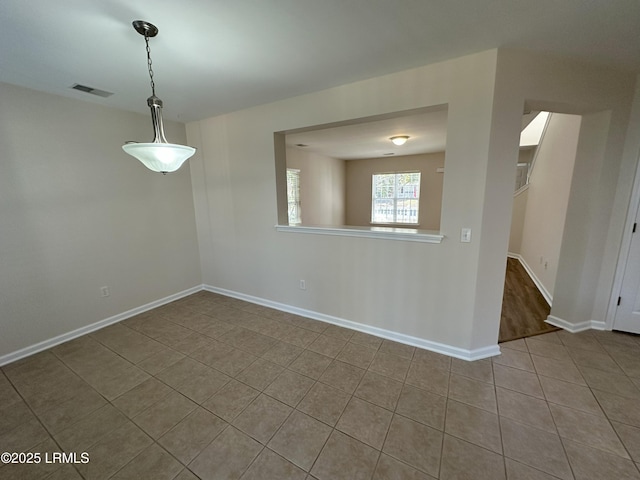 empty room with baseboards, visible vents, and tile patterned flooring