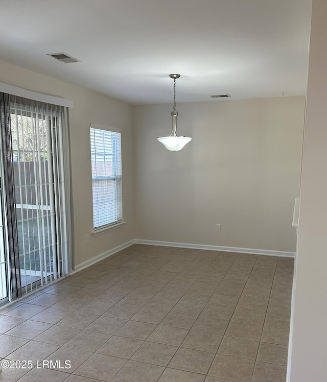 empty room featuring light tile patterned flooring, visible vents, and baseboards