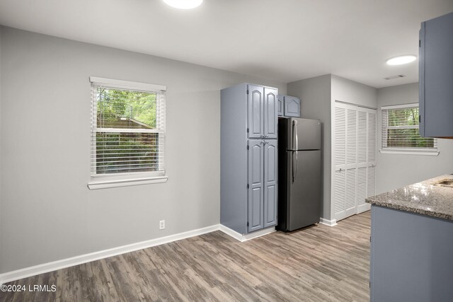 kitchen featuring gray cabinets, plenty of natural light, stone countertops, and stainless steel fridge