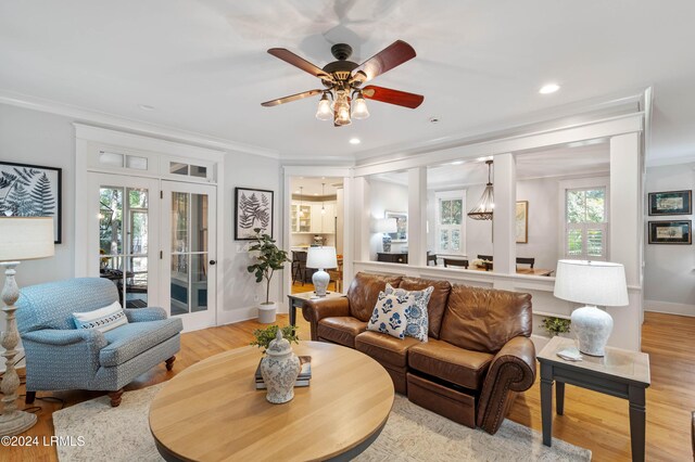 living room with crown molding, plenty of natural light, and light wood-type flooring