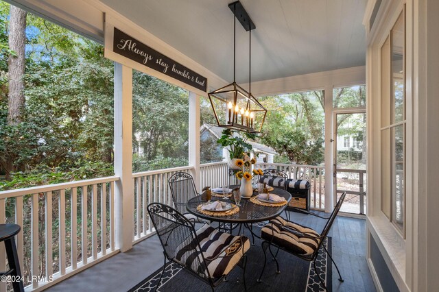 sunroom / solarium featuring a healthy amount of sunlight and a chandelier