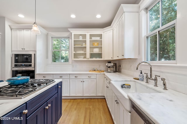 kitchen featuring blue cabinets, sink, pendant lighting, stainless steel gas stovetop, and white cabinets