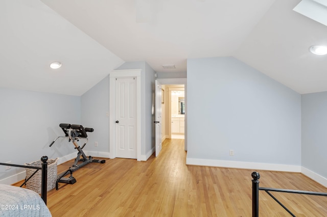 exercise area featuring lofted ceiling and light wood-type flooring