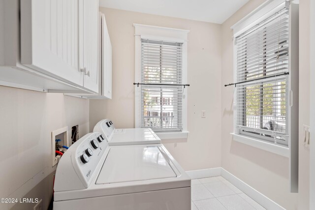 washroom with cabinets, washing machine and dryer, and light tile patterned floors