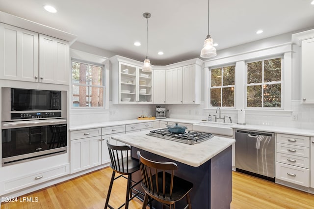 kitchen with white cabinetry, appliances with stainless steel finishes, a kitchen bar, and a kitchen island