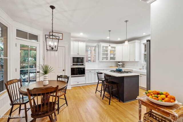 kitchen with white cabinetry, appliances with stainless steel finishes, a center island, and decorative light fixtures