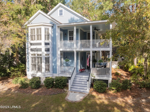 view of front of home with a front yard, a balcony, ceiling fan, and a porch