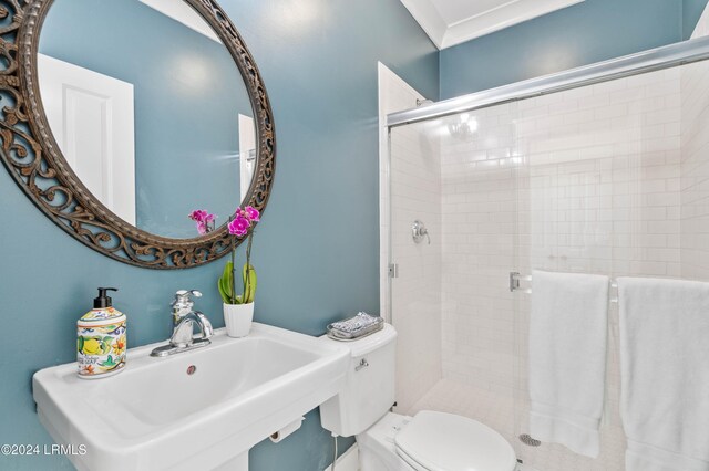 bathroom featuring toilet, a shower with shower door, and sink