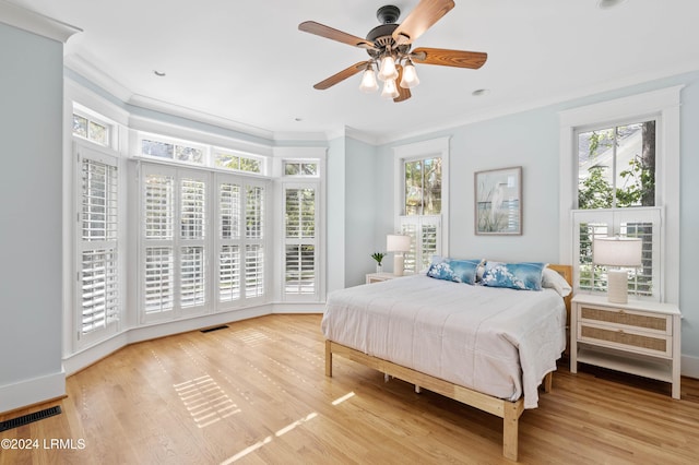 bedroom featuring light hardwood / wood-style flooring, ornamental molding, and ceiling fan