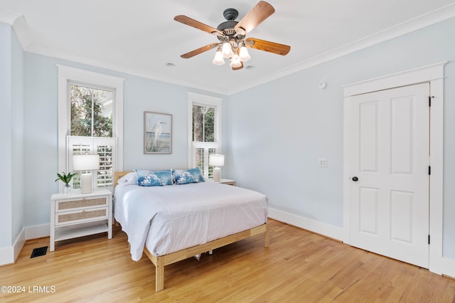 bedroom with ceiling fan, ornamental molding, multiple windows, and light wood-type flooring