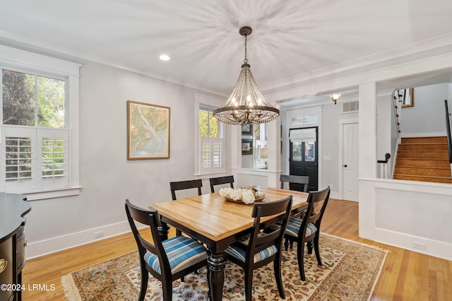 dining area featuring crown molding, an inviting chandelier, and light hardwood / wood-style flooring