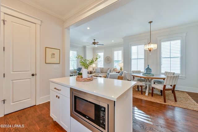 kitchen with white cabinetry, stainless steel microwave, a kitchen island, and hanging light fixtures