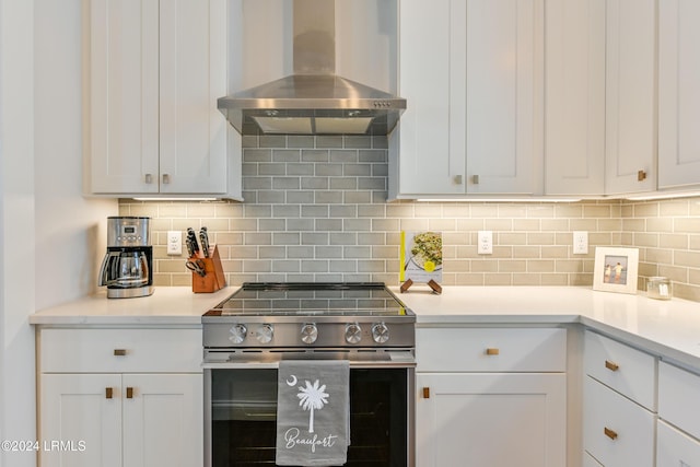 kitchen featuring ventilation hood, stainless steel electric stove, and white cabinets