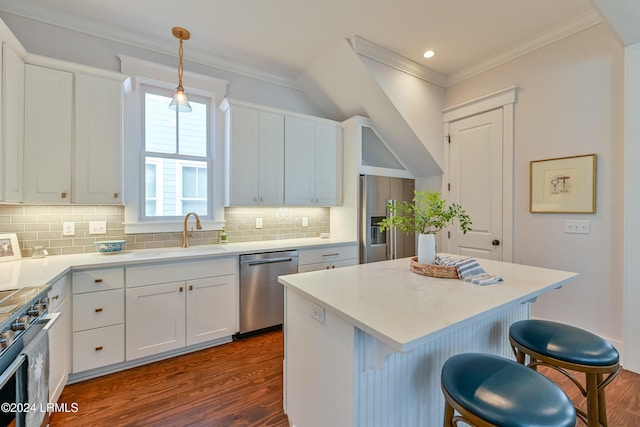 kitchen with appliances with stainless steel finishes, decorative light fixtures, white cabinetry, sink, and a center island