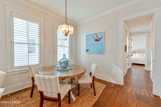 dining area with ornamental molding and dark wood-type flooring