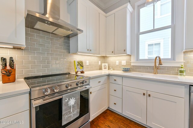 kitchen with wall chimney exhaust hood, sink, tasteful backsplash, electric stove, and white cabinets