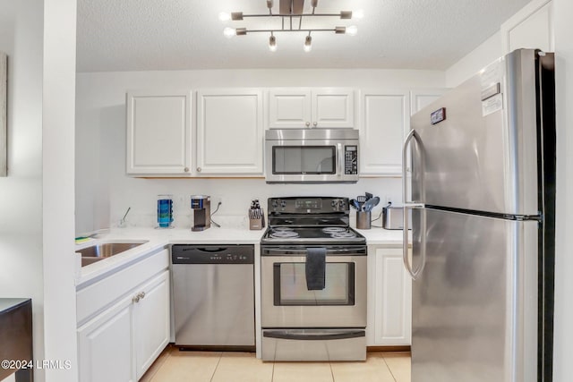 kitchen featuring appliances with stainless steel finishes, white cabinetry, sink, light tile patterned floors, and a textured ceiling