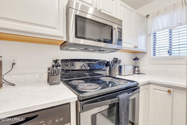 kitchen with white cabinetry, appliances with stainless steel finishes, and light stone countertops