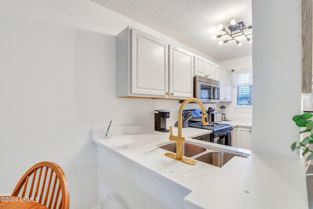 kitchen with sink, a textured ceiling, appliances with stainless steel finishes, kitchen peninsula, and white cabinets