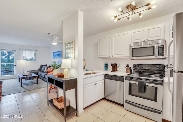 kitchen featuring stainless steel appliances, white cabinetry, sink, and light tile patterned flooring