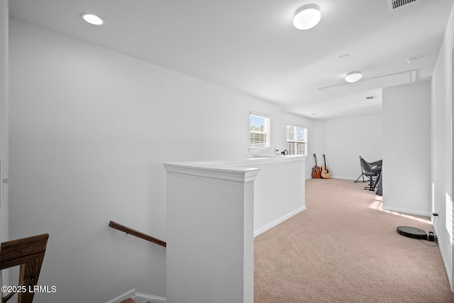 corridor with baseboards, an upstairs landing, attic access, and light colored carpet