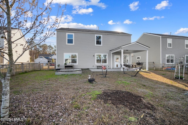 rear view of property featuring a fenced backyard, a lawn, and a patio