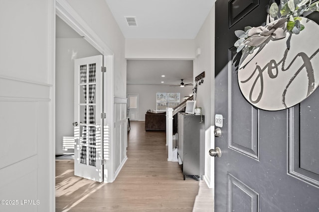 foyer entrance with visible vents, ceiling fan, and light wood finished floors