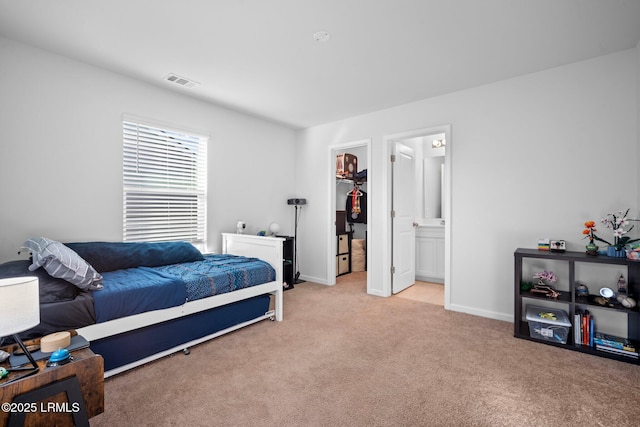 bedroom featuring light carpet, visible vents, baseboards, a closet, and a walk in closet