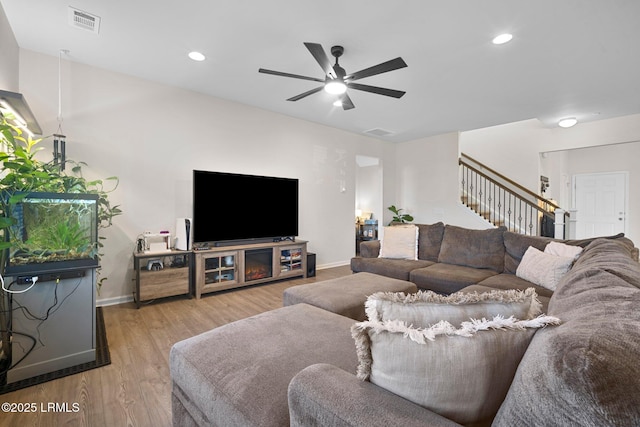 living area with baseboards, visible vents, stairway, and wood finished floors