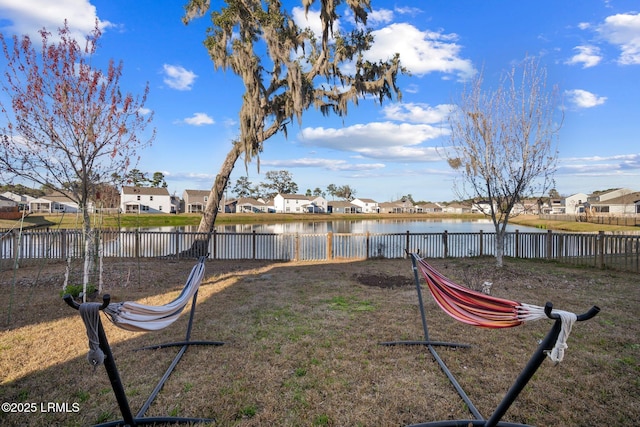 view of yard featuring a water view, a residential view, and fence