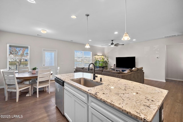 kitchen featuring white cabinets, dishwasher, hanging light fixtures, a kitchen island with sink, and a sink