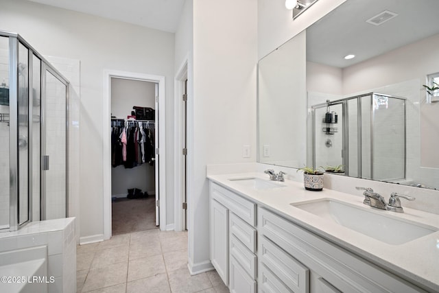 full bathroom with a stall shower, visible vents, a walk in closet, and a sink