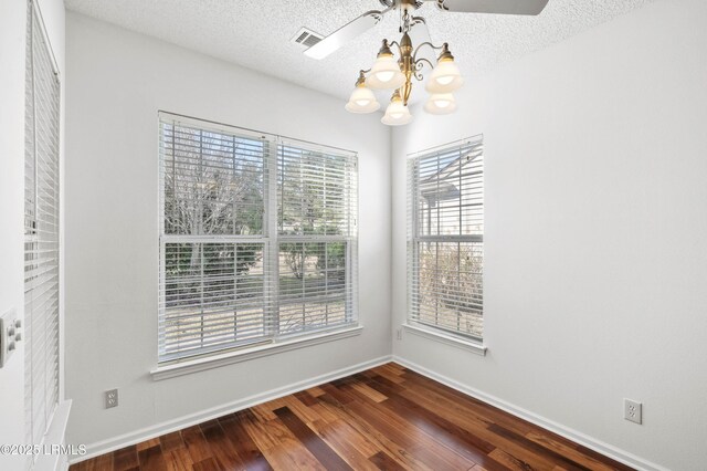 unfurnished dining area featuring visible vents, baseboards, dark wood-style floors, a notable chandelier, and a textured ceiling